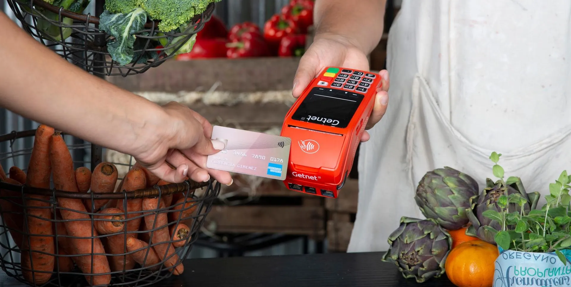 Mulher realizando compra com telemóvel  e cartão de débito Santander